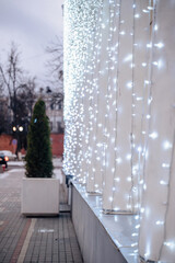 Winter outdoor walkway with string lights along a building wall.