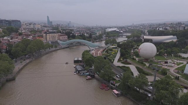Aerial view of the Bridge of Peace and Rike Park showing the contrast between the modern architecture and the natural landscape, Tbilisi, Georgia.