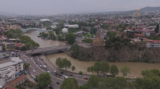 Aerial view of the Bridge of Peace over the river with the Rike park and the buildings of Tbilisi, creating a vibrant contrast, Tbilisi, Georgia.