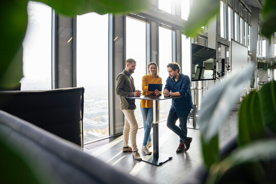 Business people discussing over tablet PC at table in office
