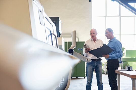 Employees discussing machinery inspection in production hall
