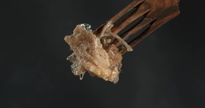 Aspic jellied meat on fork, close-up footage on dark background.