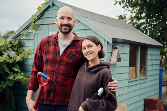 Smiling couple gardening at allotment with spade and flask