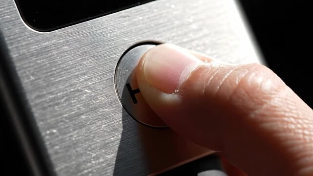 A close-up view reveals a hand delicately hovering over a polished help button, surrounded by sleek technology, capturing a moment of silent urgency and the anticipation of assistance.
