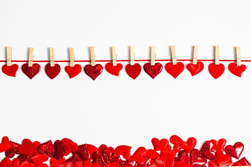 Many red heart shape attached by clothespin to a string over white background and with many hearts below. Love and Valentines Day frame concept.
