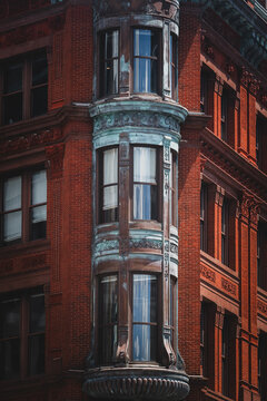 View of aged brick architecture with ornate details and a distinctive rounded corner bay window reflecting the sky, Washington D.C., District of Columbia, USA.