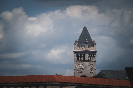 View of a stone clock tower rises majestically against a backdrop of swirling clouds, contrasting with the red-tiled rooftops below, Washington D.C., district of columbia, USA.