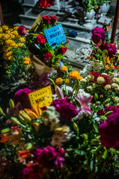 Santa Maria del Tule, Mexico - 03 November 2023: View of vibrant marigolds and roses adorn graves at Day of the Death cementary, a colorful offering against the somber stones.