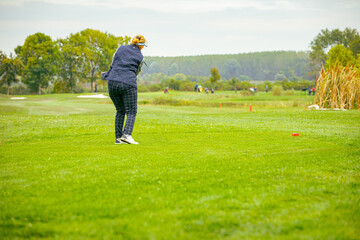 Woman golfer performs a strong golf shot to fairway