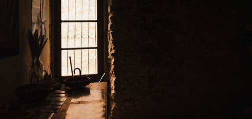 A rustic interior in a cozy traditional house with stone walls and floor and sun light through a...