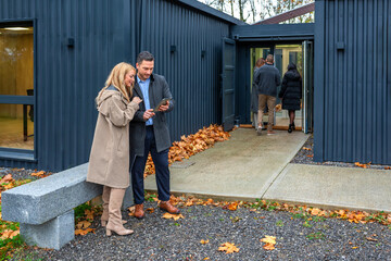 Business people discussing with digital tablet outside as coworkers entering to work in a modern office building constructed from shipping containers. Sustainable and eco friendly architecture concept