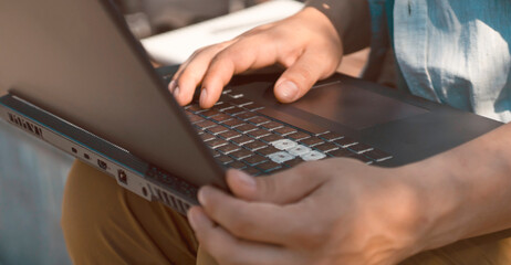 Man is typing, working on a laptop, hands on a keyboard closeup