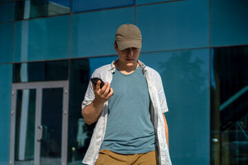 A man is holding a smartphone, walking in the city outdoors.