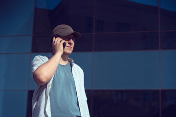 A man is holding a smartphone, walking in the city outdoors.