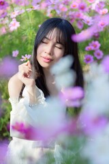 Fototapeta premium Beautiful Woman Smiling with Flowers in a Colorful Spring Field