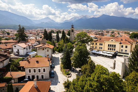 Aerial view of terracotta roofs and sun-drenched buildings nestle beneath the Pirin Mountains, with the Holy Trinity Church standing tall, Bansko, Blagoevgrad Province, Bulgaria.