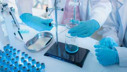 Two female scientists in white lab coats working together in a bright laboratory with microscopes, glassware, and blue test tubes, representing teamwork and modern scientific research environment.