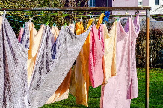 Colorful laundry drying on a clothesline in the bright sunshine on a green lawn