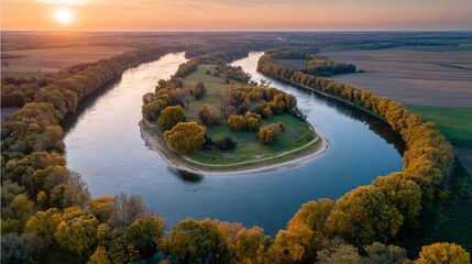 Aerial view of a winding river at sunset, surrounded by trees and fields