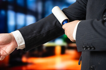 A businessman cleans his suit with a roller. Keeping clothes clean when you have pets. Pet hair problem.