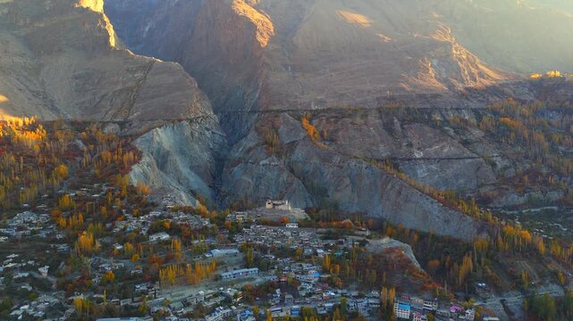 Aerial view of Baltit Fort nestled among rugged mountains and autumn trees, creating a stunning contrast of textures and tones, Karimabad, Gilgit Baltistan, Pakistan.