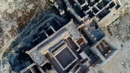 Drone revealing dense cluster of buildings on Kish Island coastline. Daytime aerial view of developed resort area with turquoise sea nearby.