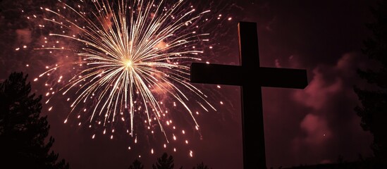 Silhouetted Christian Cross Against Night Sky with Bright Fireworks Display