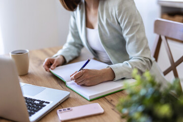 Remote work, window and writing with woman in home office for agenda, planning or research. Desk, notebook and view with freelance employee in apartment for schedule of small business startup.