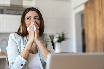 Remote work from home, sneeze and woman with a laptop, sick and illness with fatigue. Female person, freelancer or entrepreneur blowing her nose, virus and flu with online consultation with allergies.