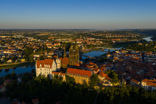 Aerial view of the majestic Meissen Cathedral and Albrechtsburg Castle stand proudly over the Elbe River, bathed in golden sunlight, Meissen, Sachsen, Germany.
