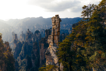 Aerial view of towering sandstone pillars piercing the mist-shrouded mountains, lush greenery clinging to their sides, Zhangjiajie National Forest Park, Zhangjiajie, Hunan, China.
