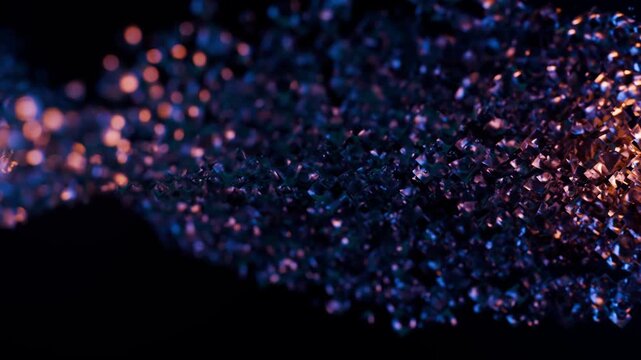 Abstract flowing structure made of glossy crystals illuminated in deep blue and warm orange tones. Detailed animation of glass particles stream in dark space with depth of field effect. 4K 60fps