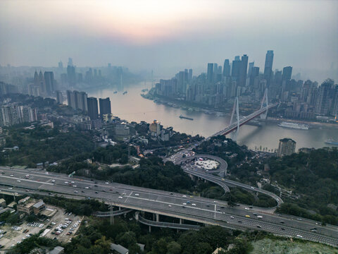 Aerial view of the Jialing River snaking through the heart of the city, with bridges connecting dense skylines under a hazy, muted sunset, Chongqing, Chongqing, China.