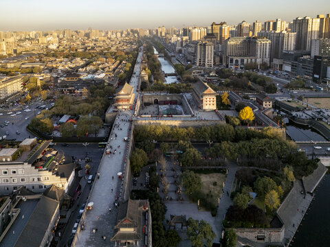 Aerial view of the Xi'an City Wall, a majestic ancient fortification bathed in the glow of the setting sun, with modern buildings in the background, Xi'An, Shaanxi, China.