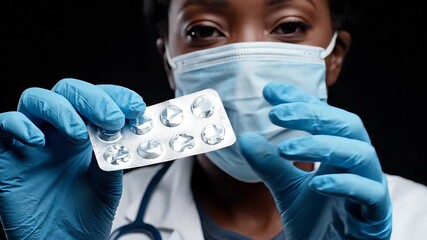 A dedicated medical professional wearing protective blue gloves and a surgical face mask carefully presents a blister pack of essential medication symbolizing healthcare treatment and pharmaceutical .
