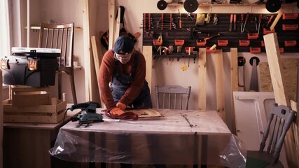 Professional female furniture restorer replacing old upholstery on vintage wooden chair in her workshop