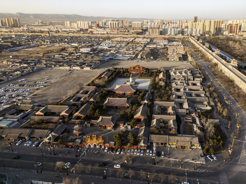 Aerial view of the serene Huayan Temple, an oasis of traditional architecture amidst the modern cityscape, bathed in the soft glow of the setting sun, Datong, Shanxi, China.