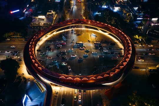Aerial view of the vibrant Jin Hui Xi Yi Jie pedestrian bridge, a glowing ring amidst the bustling city lights, Cheng Du Shi, Si Chuan Sheng, China.