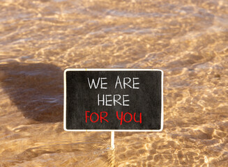 Naklejka premium Support, help and we are here for you symbol. Concept words We are here for you on beautiful blackboard. Beautiful Red sea water background. Business we are here for you concept. Copy space.