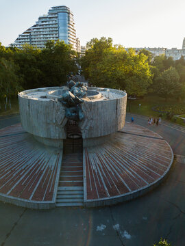 Aerial view of the Pantheon of the Fallen Antifascists monument, its concrete structure radiating outward under the soft glow of the setting sun, Burgas, Burgas, Bulgaria.