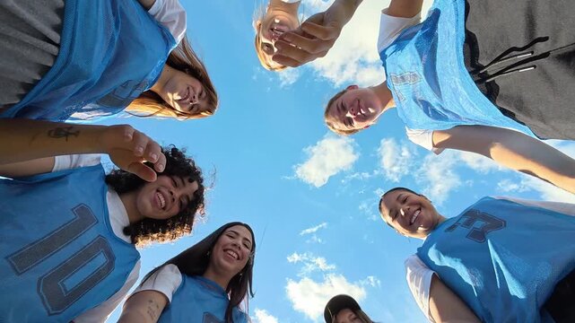 Women's sports team stacking hands in a huddle for motivation