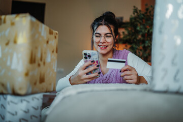 Woman shopping online with smartphone and credit card for holiday gifts