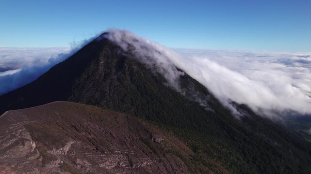 Acatenango, Guatemala - A Sweeping View of a Cloud-Covered Volcanic Slope Rises Sharply Above the Rugged Terrain - Drone Flying Forward