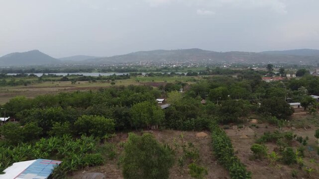 Aerial drone footage of Ghana, Africa, serene lake surrounded by mountains. Traditional boats across the water near a local village, with views near the Right to Dream Football Academy