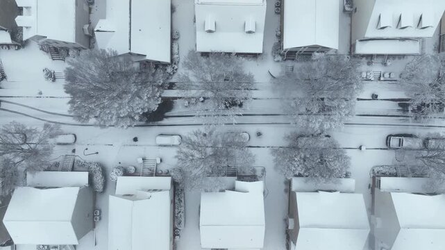 White snowy row of houses and street with tire marks in winter season. Aerial top down shot. Calm suburb neighborhood of USA.