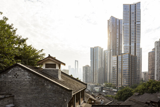 View of ancient tiled roofs juxtapose against towering, modern skyscrapers under a soft, diffused sky, a timeless blend of old and new, Chongqing, Chongqing, China.