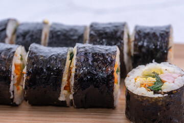 Fresh Korean gimbap rolls sliced and neatly arranged on a wooden board, showing colorful ingredients and a clean, appetizing food presentation.