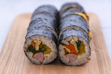 Fresh Korean gimbap rolls sliced and neatly arranged on a wooden board, showing colorful ingredients and a clean, appetizing food presentation.
