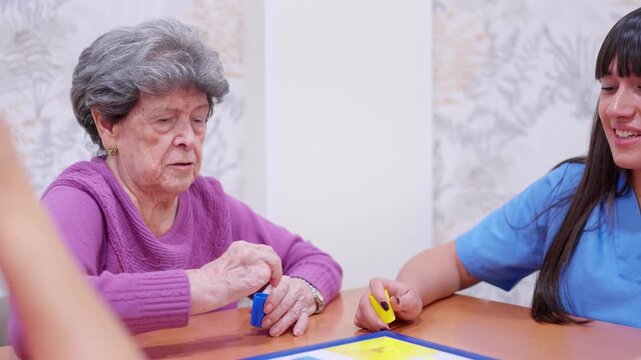 Nurse and elderly woman playing Parcheesi board game