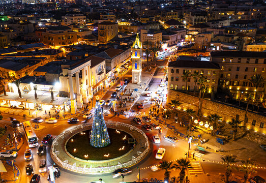 Aerial view of St. Peter church and Jaffa Clock Tower square illuminated with warm lights, contrasting with the dark night sky, Tel Aviv-Yafo, Tel Aviv District, Israel.